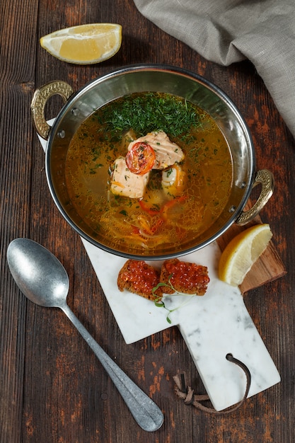 Soupe de poisson frais avec des ingrédients et des épices pour la cuisson. Fond en bois