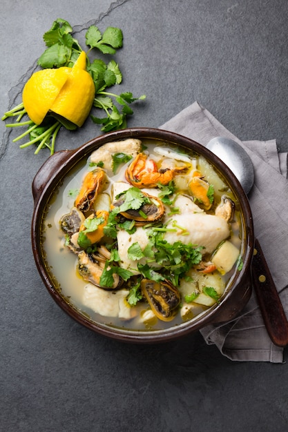 Soupe de poisson et fruits de mer dans des bols d'argile servis avec citron et coriandre.
