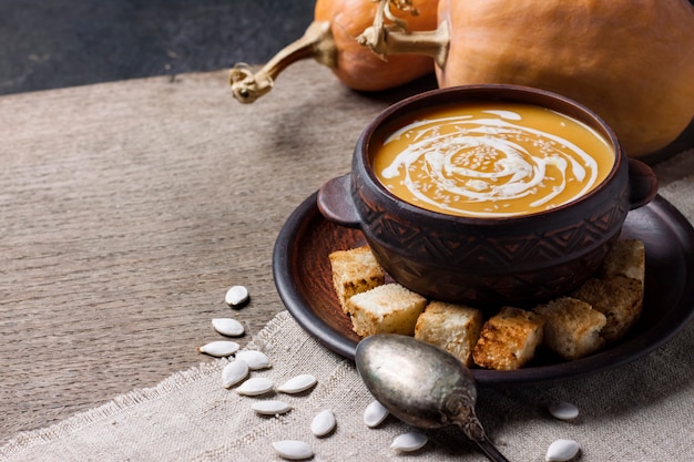 Soupe de potiron à la crème et graines de sésame avec croûtons sur une surface en bois