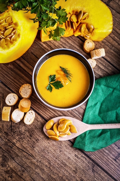 Soupe de potiron à la crème avec des herbes fraîches et des craquelins sur fond de bois foncé aliments sains sélectif fo