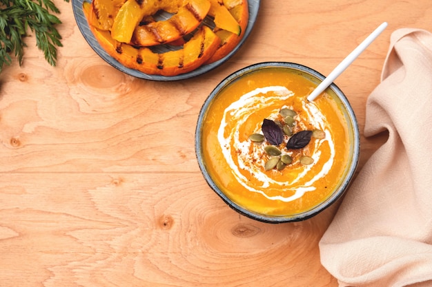 Soupe de potiron dans une assiette sur un fond en bois.