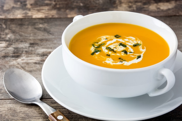 Soupe de potiron dans un bol blanc sur une table en bois