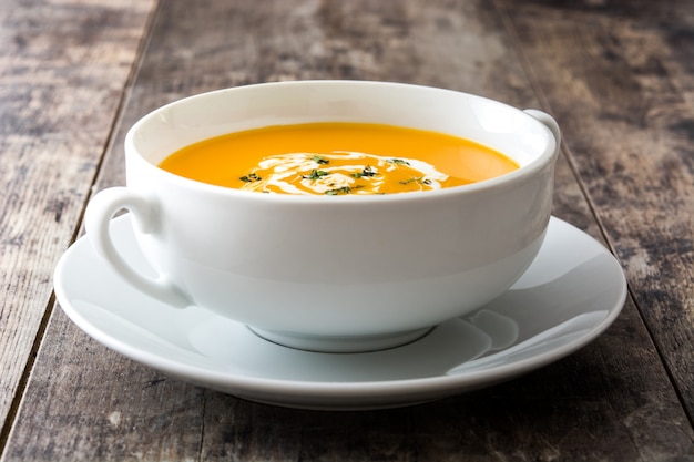 Photo soupe de potiron dans un bol blanc sur une table en bois