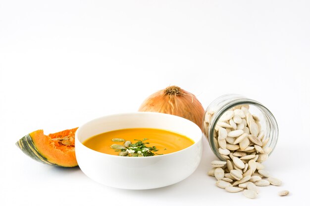 Soupe de potiron dans un bol et graines de citrouille isolés on white