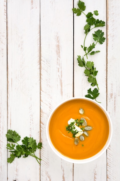 Soupe de potiron et ingrédients sur bois blanc