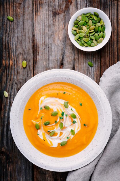 Soupe de potiron maison avec de la crème et des graines sur fond de bois