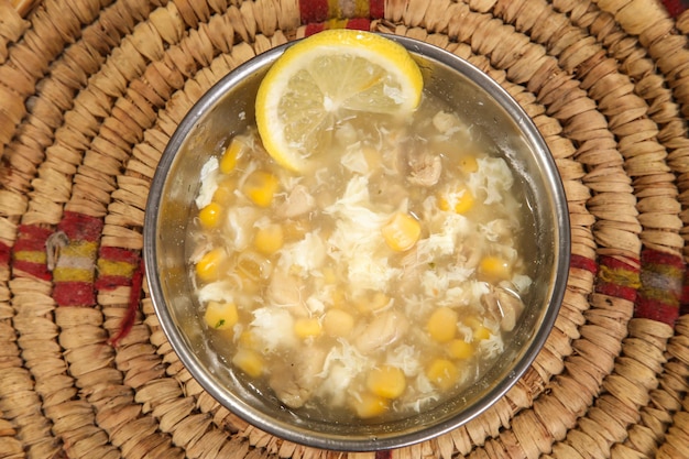 Soupe de poulet au maïs avec citron servi dans un bol isolé sur fond vue de dessus style arabe