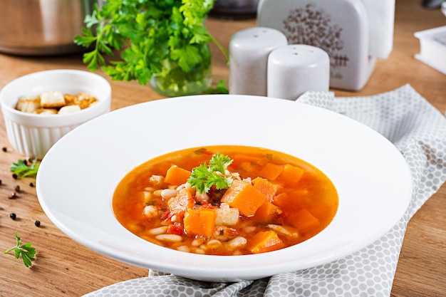 Soupe de poulet à la tomate avec de la citrouille et des haricots blancs dans un bol blanc