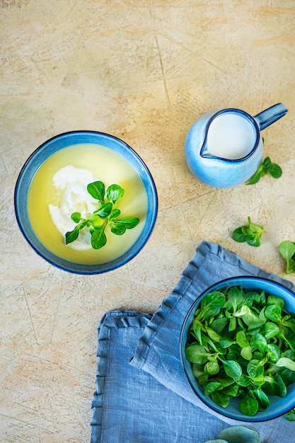 Photo soupe de purée maison de courgettes fraîches et d'épinards yang sur fond jaune clair.