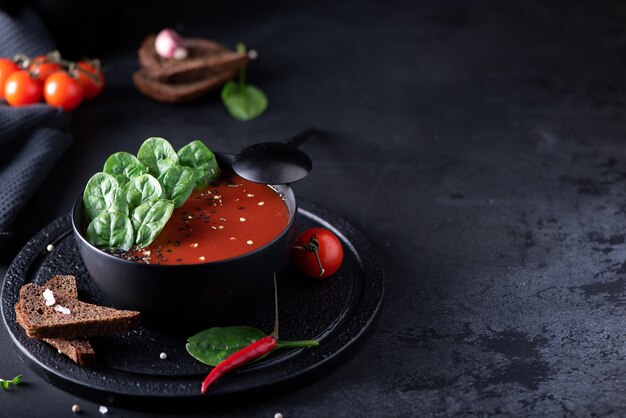 Soupe de purée de tomates aux épinards dans un bol noir, close-up