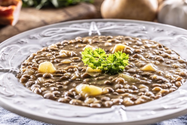 Soupe ou ragoût de lentilles et pommes de terre dans une assiette rustique décorée de persil