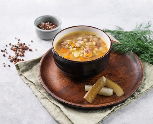 Soupe russe traditionnelle aux concombres marinés Pickle à l'orge perlé et à la viande sur fond clair avec aneth frais et épices