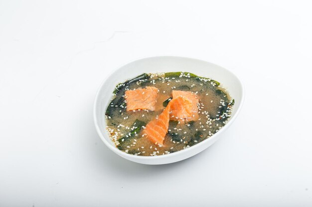 Soupe avec saumon dans une assiette sur un fond blanc isolé