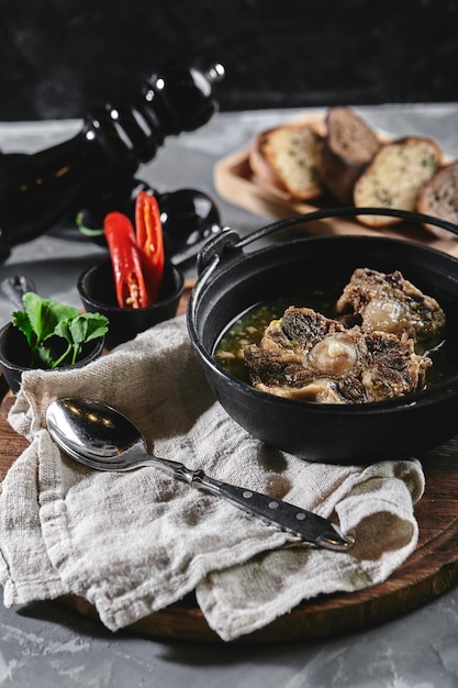 Photo soupe de shurpa dans une casserole de castiron sur la table sur un fond gris cuisine orientale traditionnelle