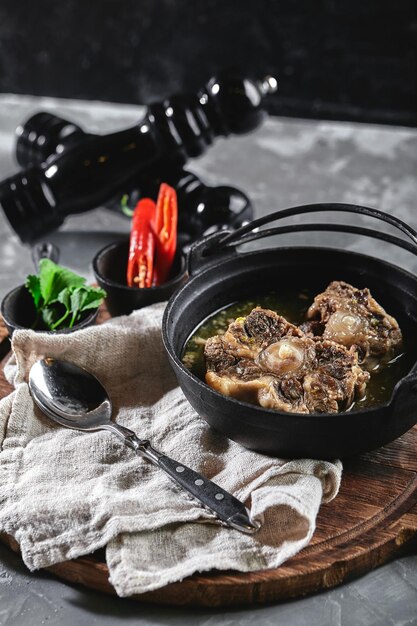 Photo soupe de shurpa dans une casserole de castiron sur la table sur un fond gris cuisine orientale traditionnelle