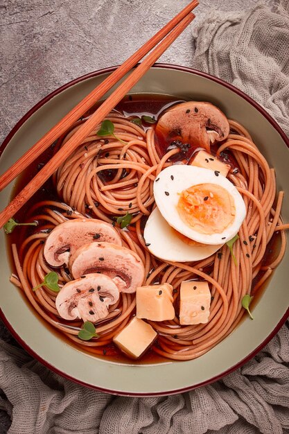 Soupe de soba asiatique avec des champignons et du fromage à l'œufs des graines de sésame faites maison sans gens