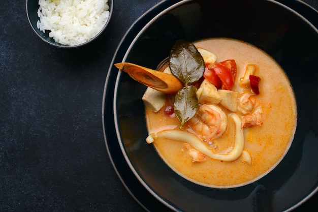 Soupe thaïlandaise aux fruits de mer et riz sur béton foncé