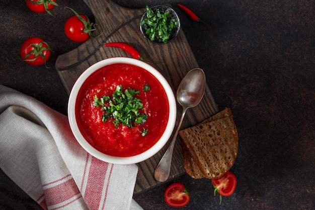 Soupe de tomates au persil vert frais dans un bol Fond sombre Gros plan Vue de dessus