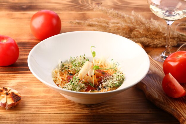 Soupe de tomates aux calmars et fromage décorée de microgreen sur table en bois et vin blanc