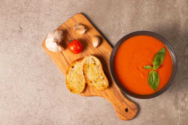 Soupe de tomates fraîches et saines avec tomates à l'ail et au basilic et pain sur fond de bois