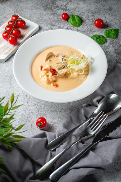 Soupe traditionnelle aux sébastes et moules servie dans une assiette blanche sur une table en pierre grise. Menu du restaurant