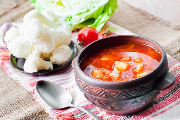 Soupe végétarienne aux tomates avec chou et chou-fleur dans un bol rustique en céramique