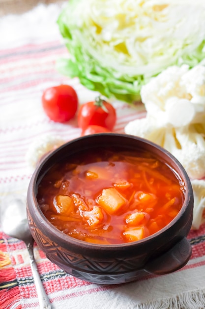 Soupe végétarienne aux tomates avec chou et chou-fleur dans un bol rustique en céramique