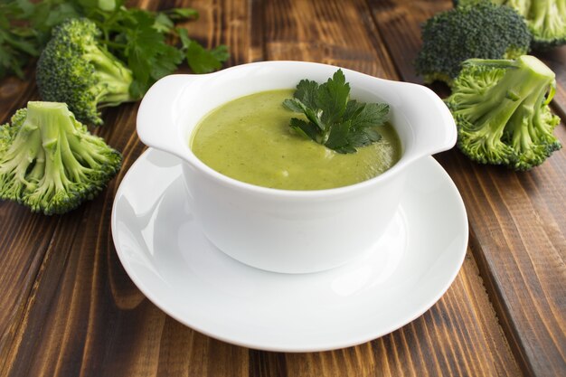 Soupe végétarienne de purée de brocoli dans e bol blanc sur le fond en bois brun