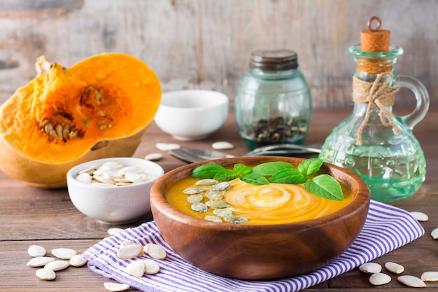 Photo soupe végétarienne de purée de potiron d'automne avec des graines et de la crème dans une assiette en bois sur la table