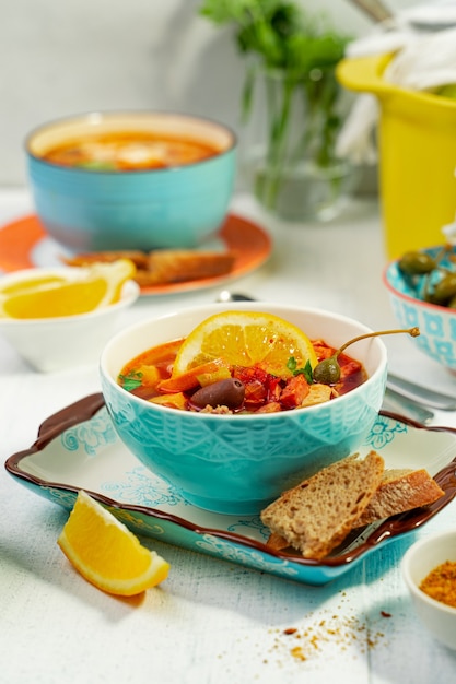 Soupe de viande de solyanka maison servie avec du citron, des olives et des câpres