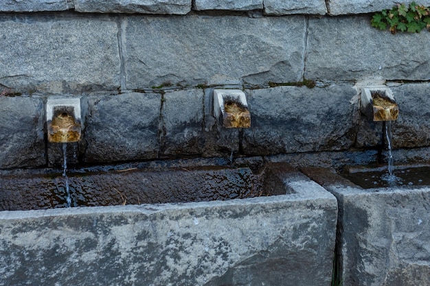 Source naturelle d'eau douce sortant de l'intérieur d'une roche par un tuyau