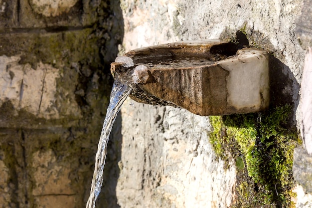 Une source en pierre libre avec de l'eau froide et claire dans les montagnes par une journée d'hiver ensoleillée Grèce Péloponnèse