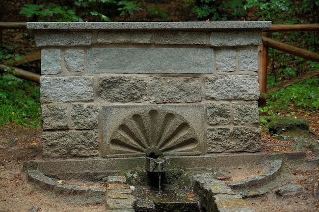 Photo source souterraine d'eau propre une source d'eau s'écoule d'un bâtiment en pierre