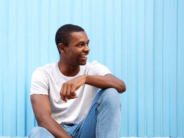 Souriant afro-américain assis sur fond bleu