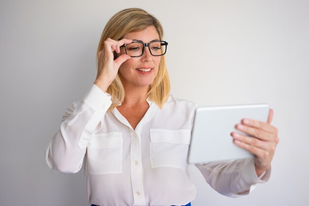 souriant d&#39;âge mûr séduisante femme blonde séduisante réglage des lunettes