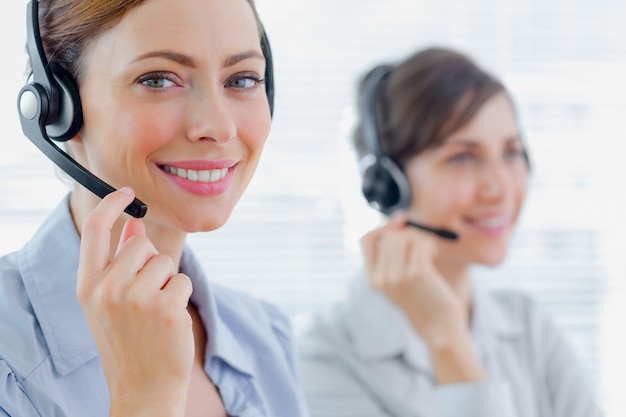 Souriant agents du centre d&#39;appel avec casques au travail