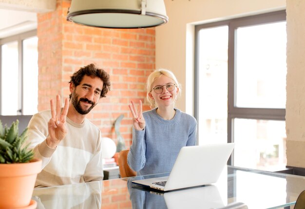 souriant et l'air amical, montrant le numéro trois ou troisième avec la main en avant, compte à rebours