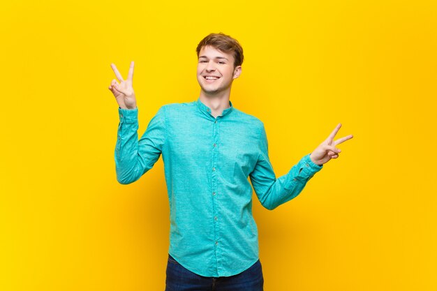 souriant et l'air heureux, amical et satisfait, gesticulant victoire ou paix à deux mains