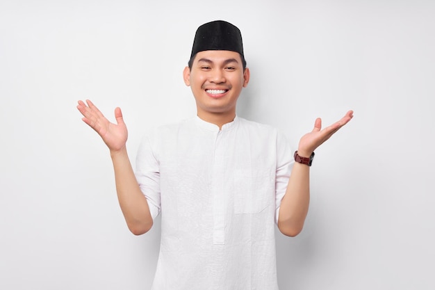 Souriant amical beau jeune homme musulman asiatique portant le costume arabe debout avec les bras levés larges et accueillant le Ramadan isolé sur fond blanc Les gens concept de style de vie islamique religieux