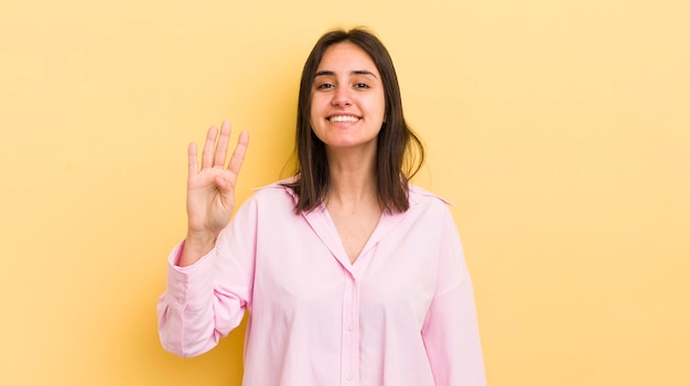 Souriant et amical montrant le numéro quatre ou quatrième avec le compte à rebours de la main vers l'avant