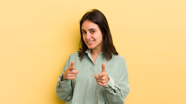 Souriant avec une attitude heureuse et réussie positive pointant vers la caméra faisant signe de pistolet avec les mains