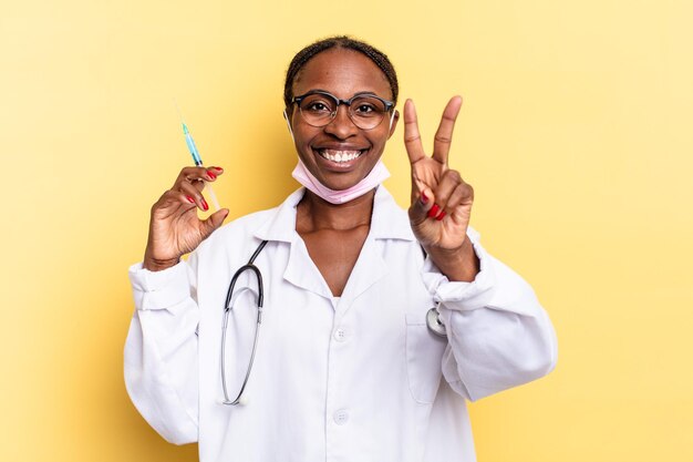 Souriant et ayant l'air heureux, insouciant et positif, gesticulant la victoire ou la paix d'une main. concept de médecin et de seringue