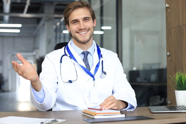 Souriant beau médecin de sexe masculin parlant à la caméra avec le patient.