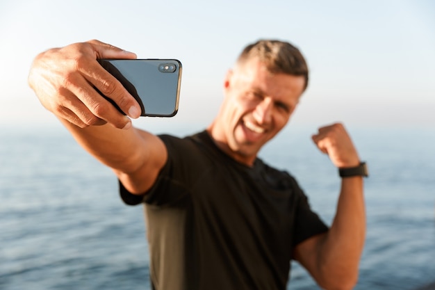 Souriant beau sportif torse nu prenant un selfie