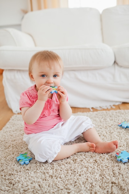 Souriant bébé jouant avec des pièces de puzzle tout en étant assis sur un tapis