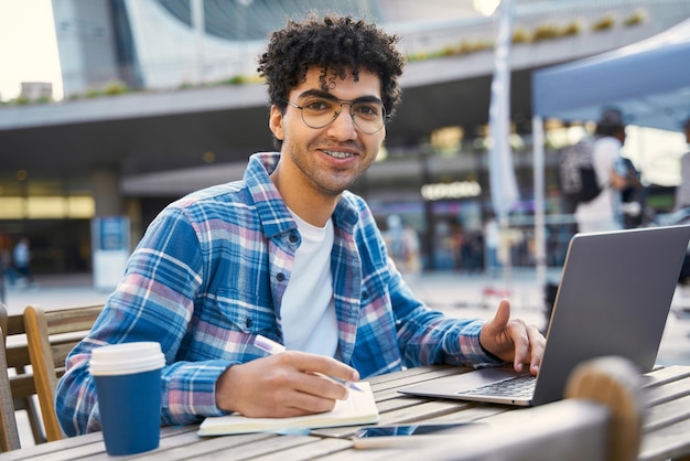 Souriant bel étudiant moyen-oriental étudiant à l'aide d'un ordinateur portable, concept d'éducation en ligne