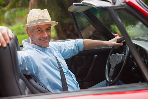 Souriant bel homme posant en rouge décapotable