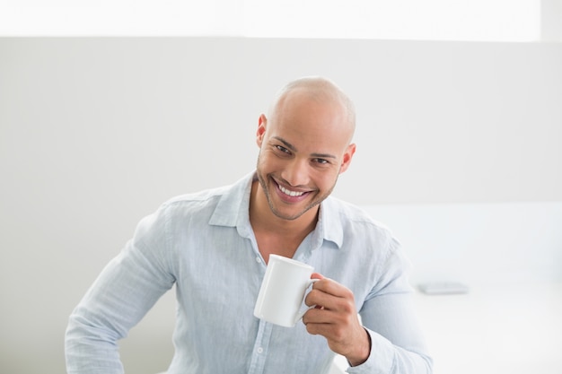 Souriant bel homme tenant une tasse de café à la maison