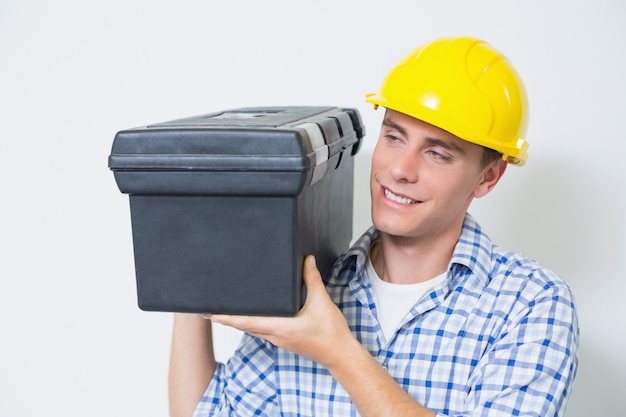 Souriant bricoleur dans un coffre-fort jaune portant la boîte à outils