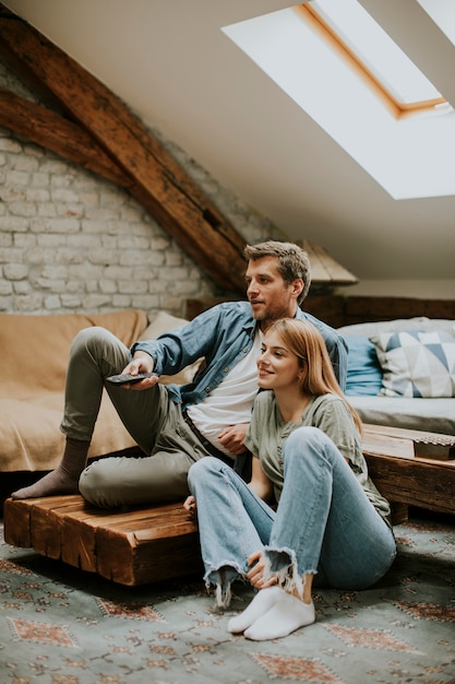 Souriant charmant jeune couple se détendre et regarder la télévision à la maison